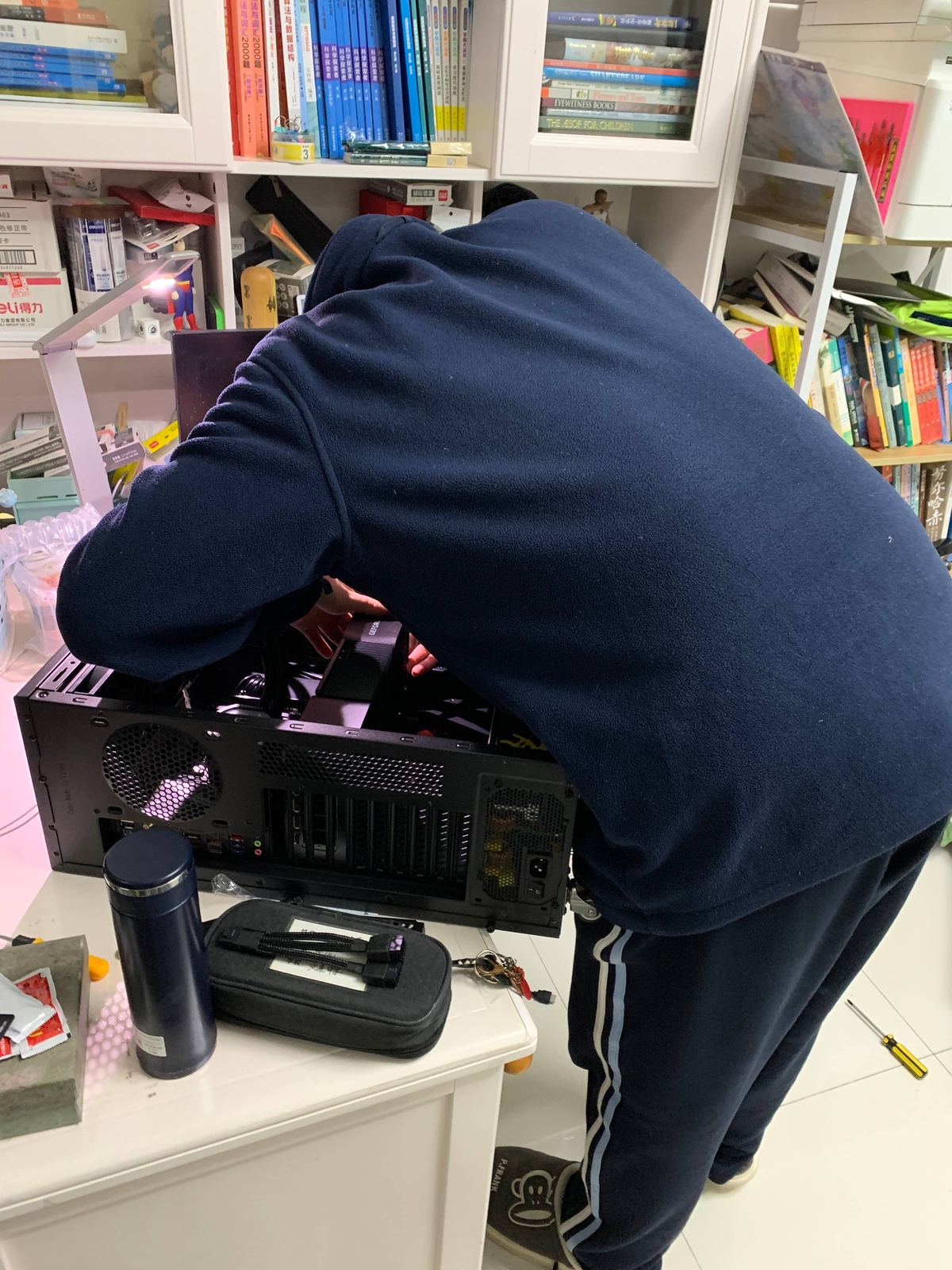 Tianqiqi leaning over an open computer case while assembling it