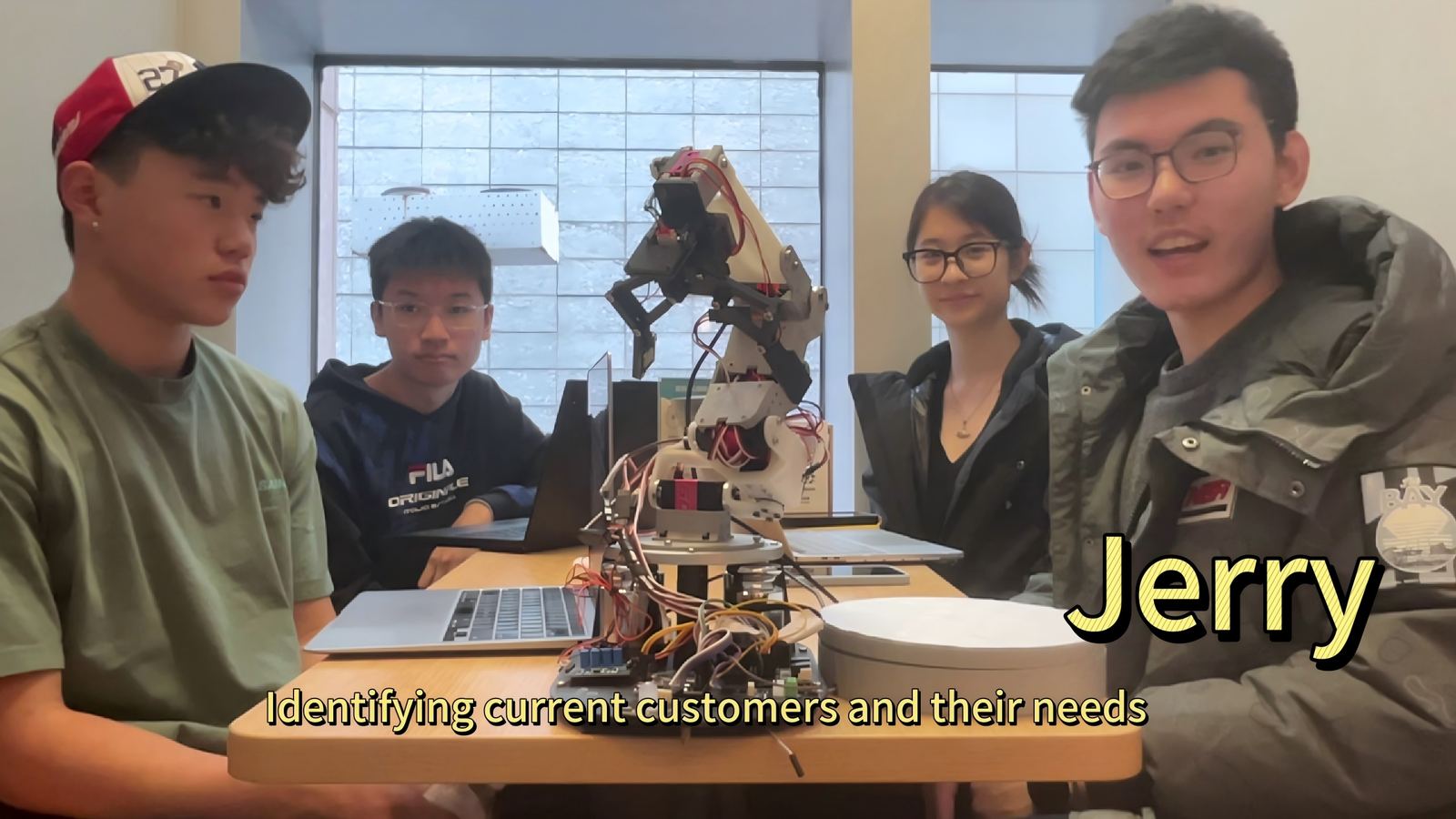Conrad team around a robotic arm, with Jerry labeled as the member covering customer needs